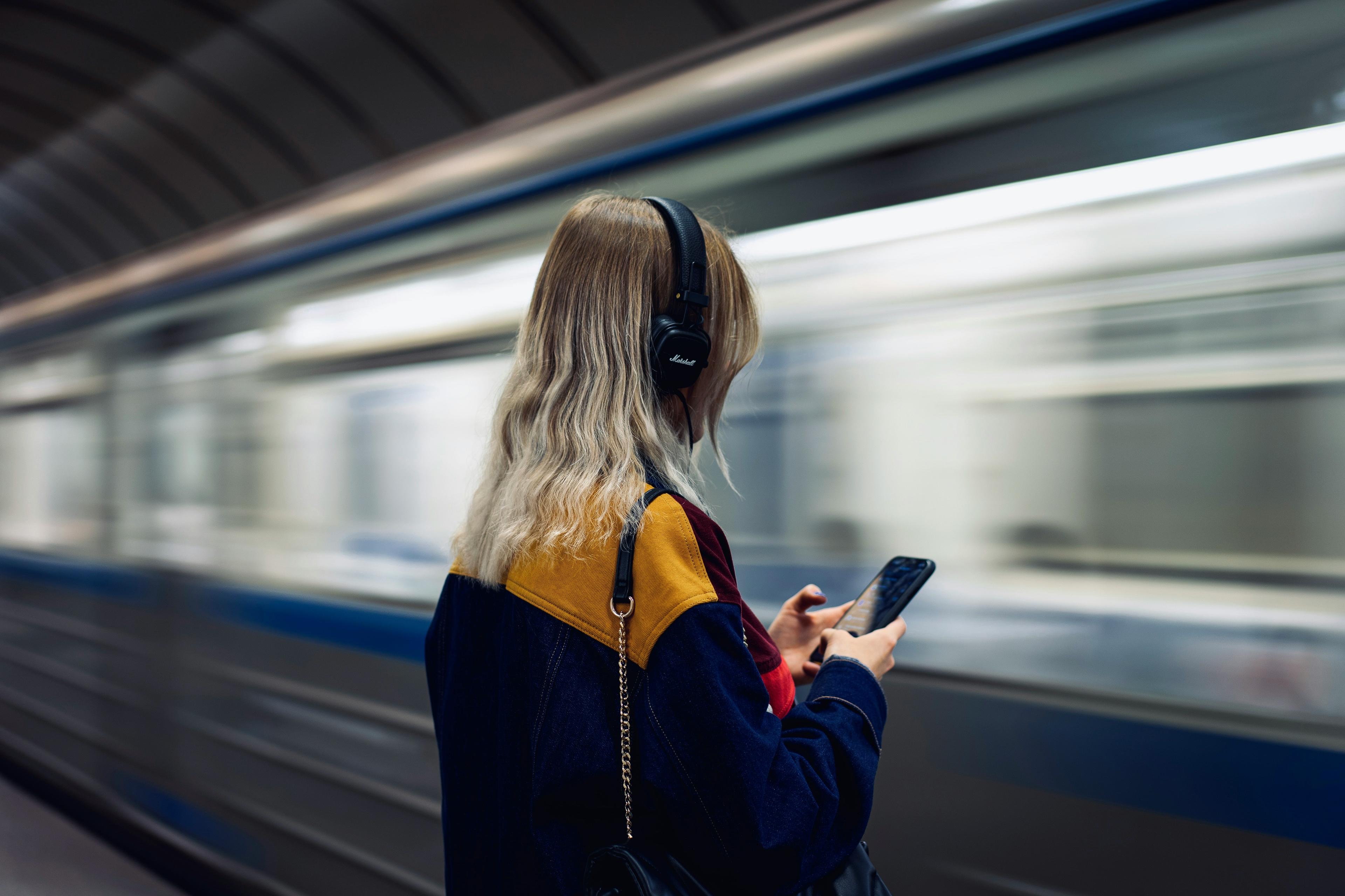 Woman listening to a podcast with headphones while commuting